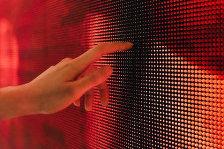 Closeup of womans hand touching illuminated LED screen