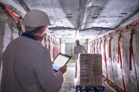 Worker checking products freezer truck tablet