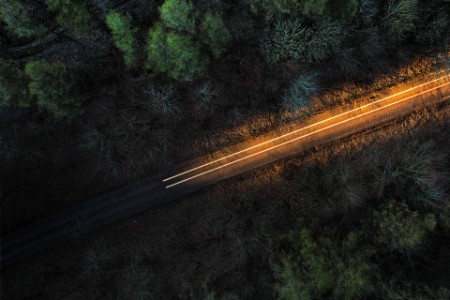 Drone view above a road through a forest at night