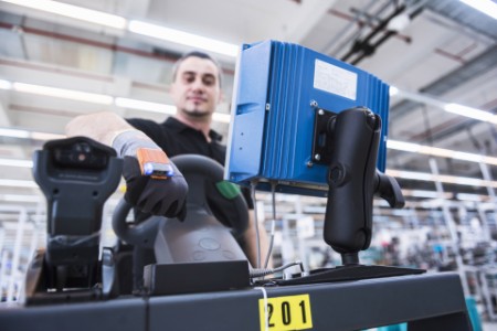 ey-man-with-wearable-scanner-on-tugger-train-in-factory-shop-floor