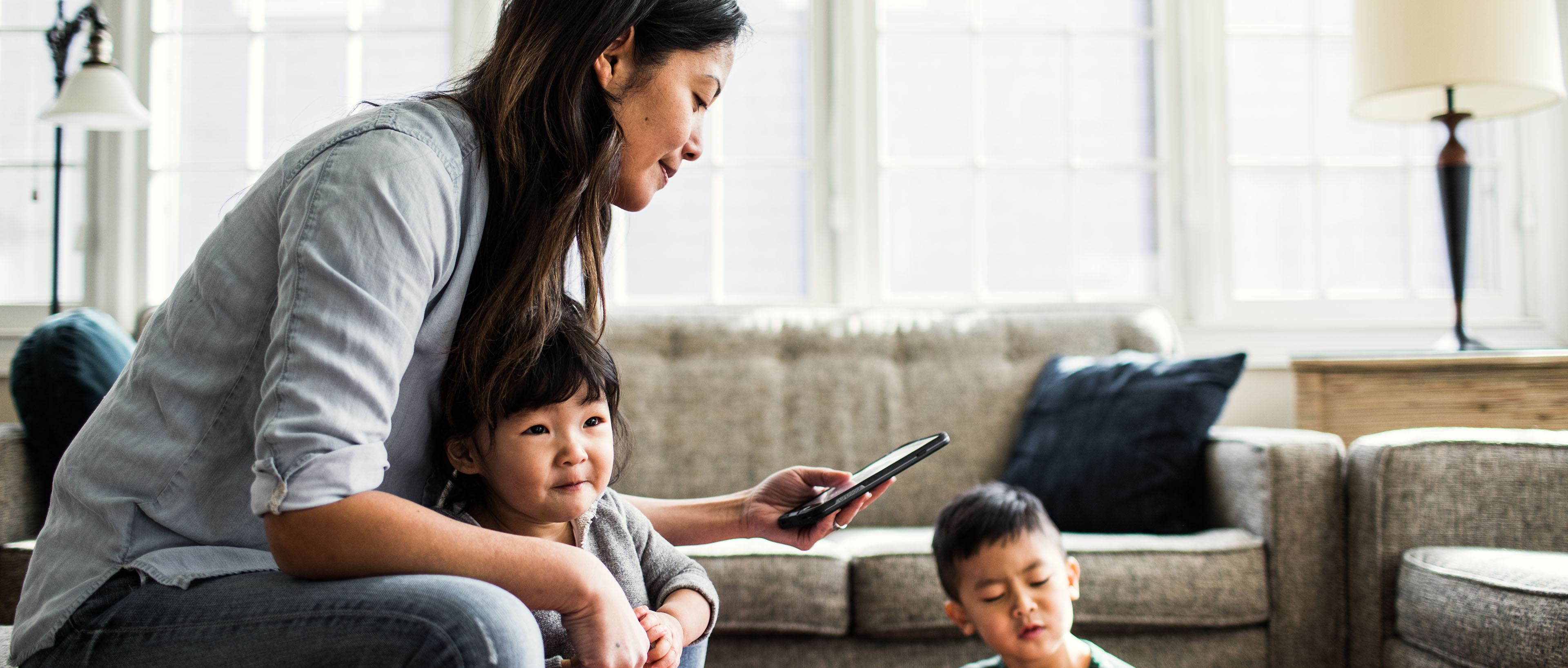 Mother using smartphone with children present  