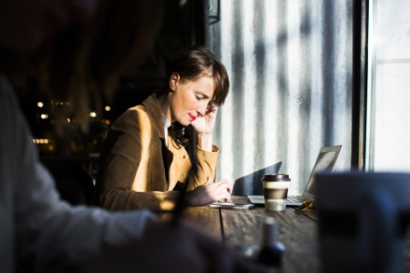 Side view of woman using smart phone while sitting at cafe table