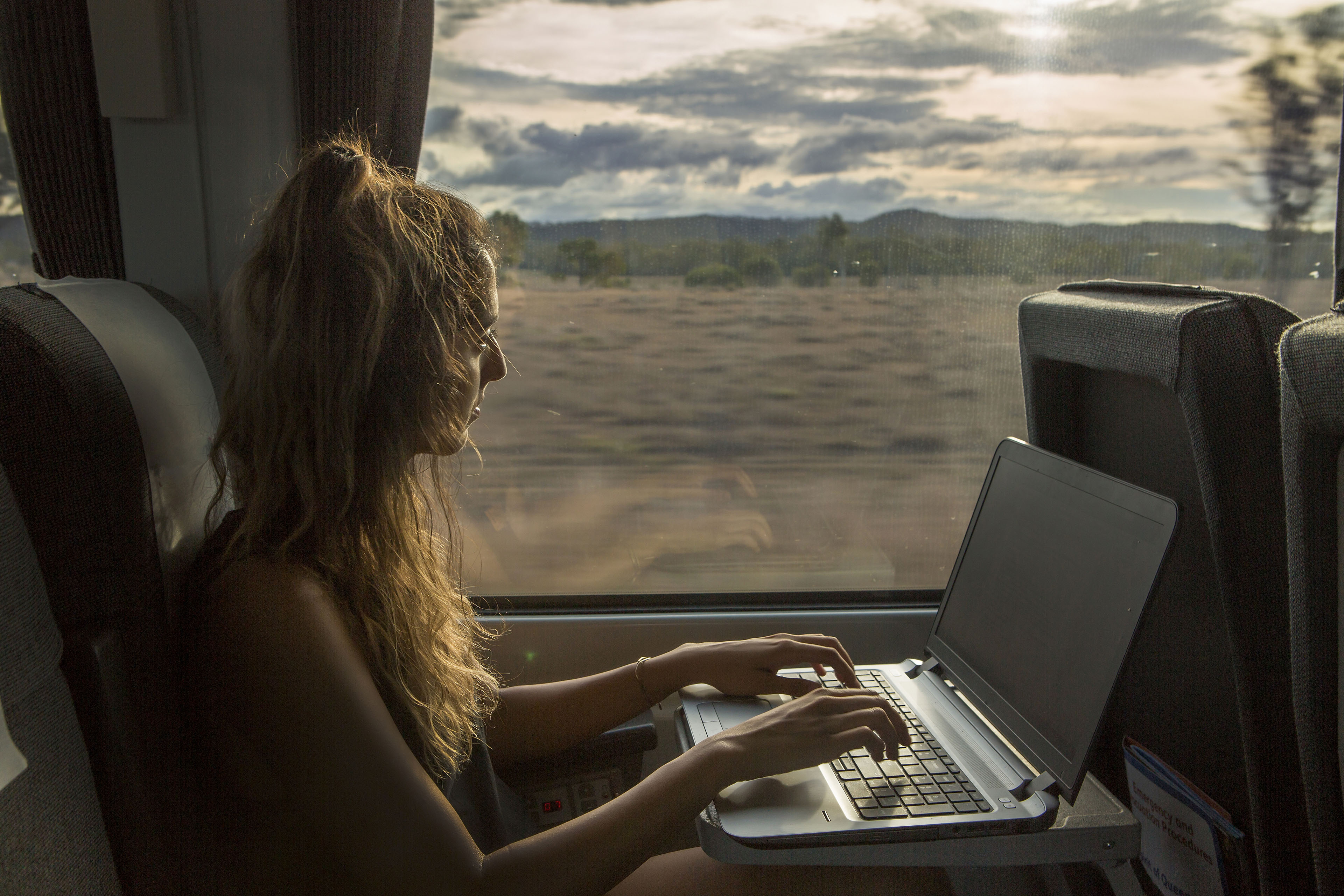 A woman working on her laptop while traveling on a train