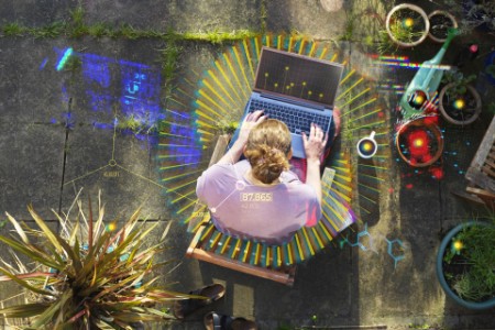Vista elevada de una mujer trabajando desde casa en su jardín usando una computadora portátil