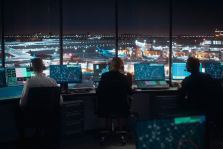 Equipe de controle de tráfego aéreo trabalhando em uma torre de controle moderna de aeroporto à noite