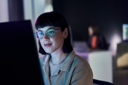Business woman coding on a computer in a dark room