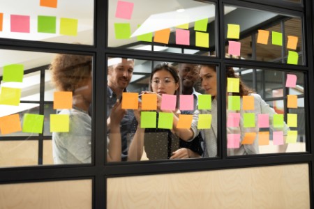 Diverse team assigning projects using multicolored sticky notes