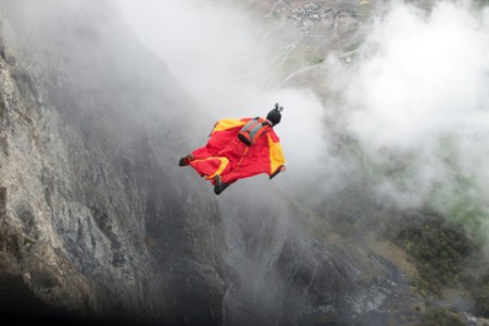 Wingsuit proximity flyer is diving down the cliff
