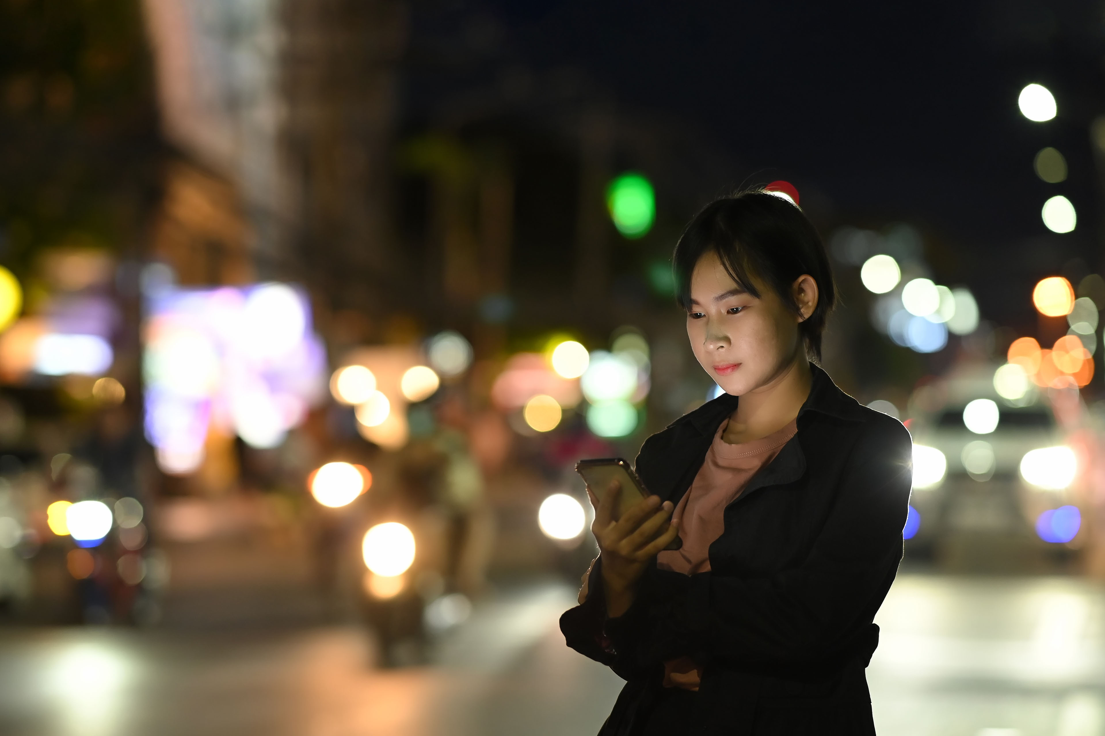 
            亚洲女人使用运输应用程序，等待私人出租车
        