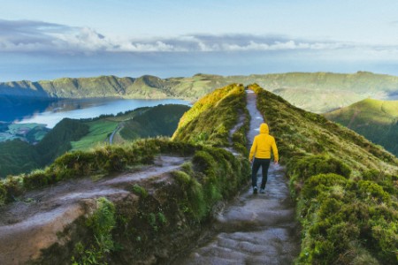 Azor adalarında volkanik krater önünde sarı yağmurluklu yürüyüşçü