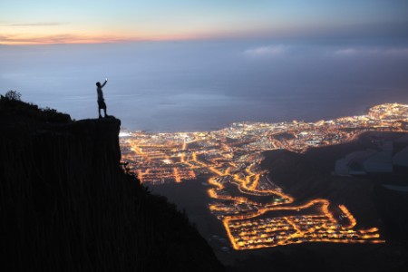 man with mobile device overlooking city at night hero image