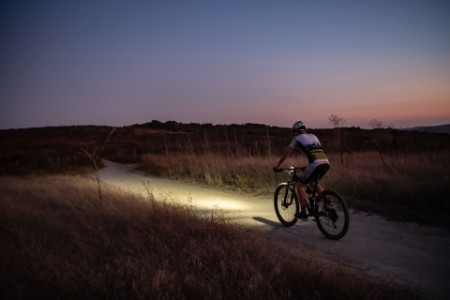 night mountain bike rider with a light at sunset