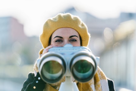 Woman in beret using public viewing binoculars