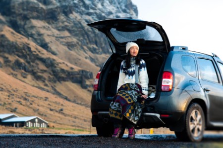 Female traveler enjoying iceland view from the car trunk