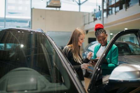 Sales manager sharing the car details with woman customer at auto dealership