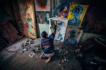 Artista trabalhando em pintura em estúdio com materiais de arte ao seu redor