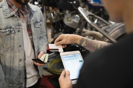 Client payant un mécanicien sur une tablette numérique avec lecteur de carte