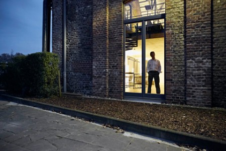 Vista exterior de hombre de pie en la ventana de un edificio moderno por la noche