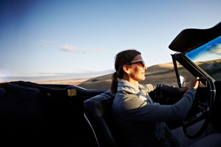 Mature woman driving convertible at sunset
