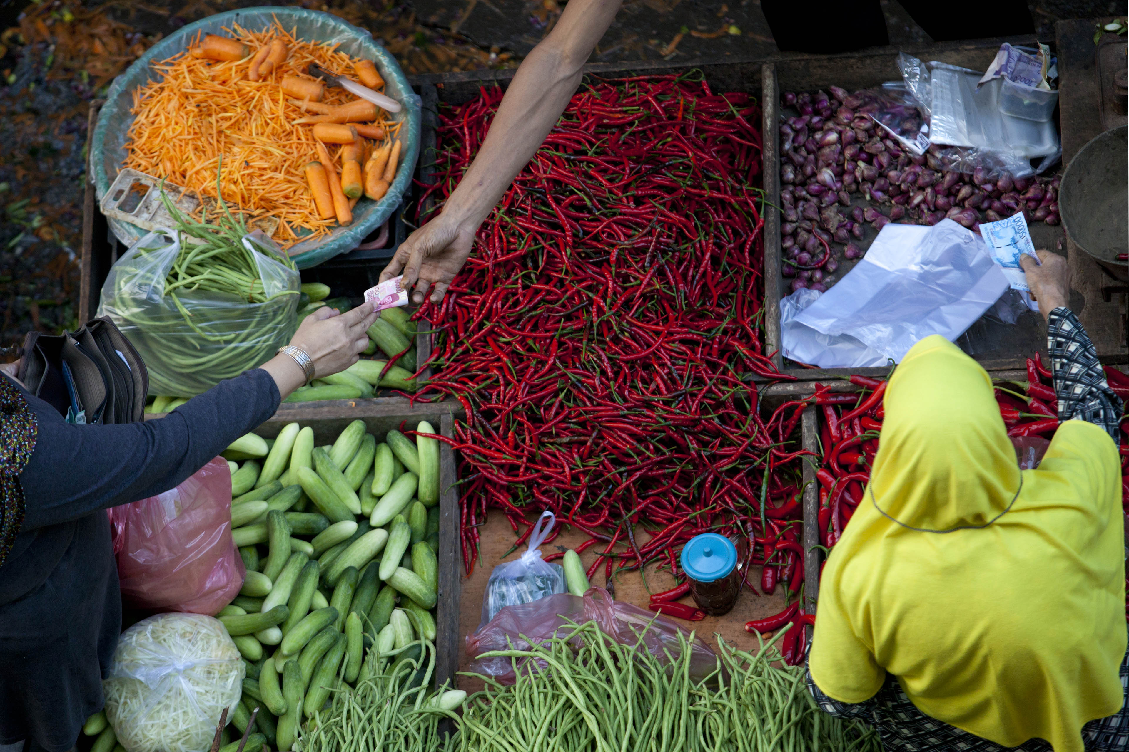People exchanging money vegetables market stall image