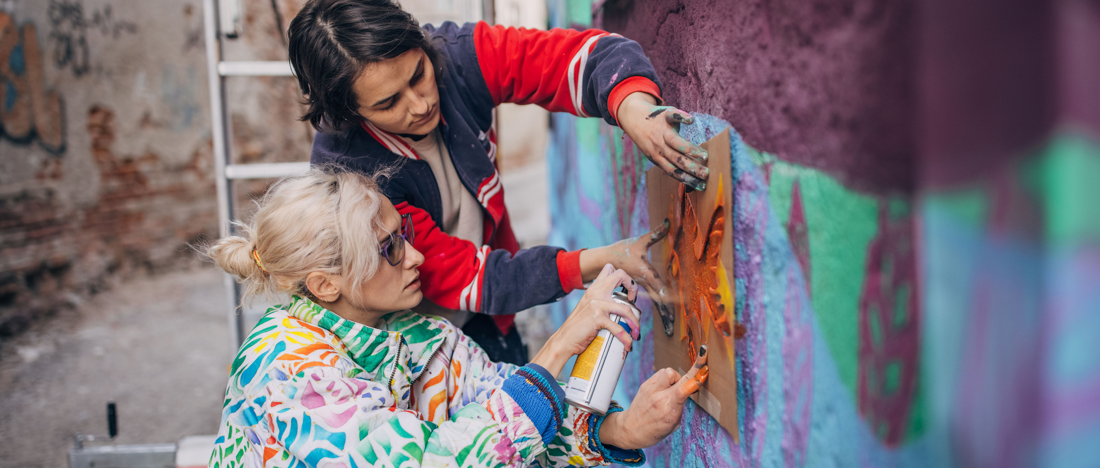 Sokak sanatçıları bina duvarına sprey boya ile resim yapıyor