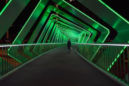 Mujeres cruzan un puente peatonal con efectos de luz