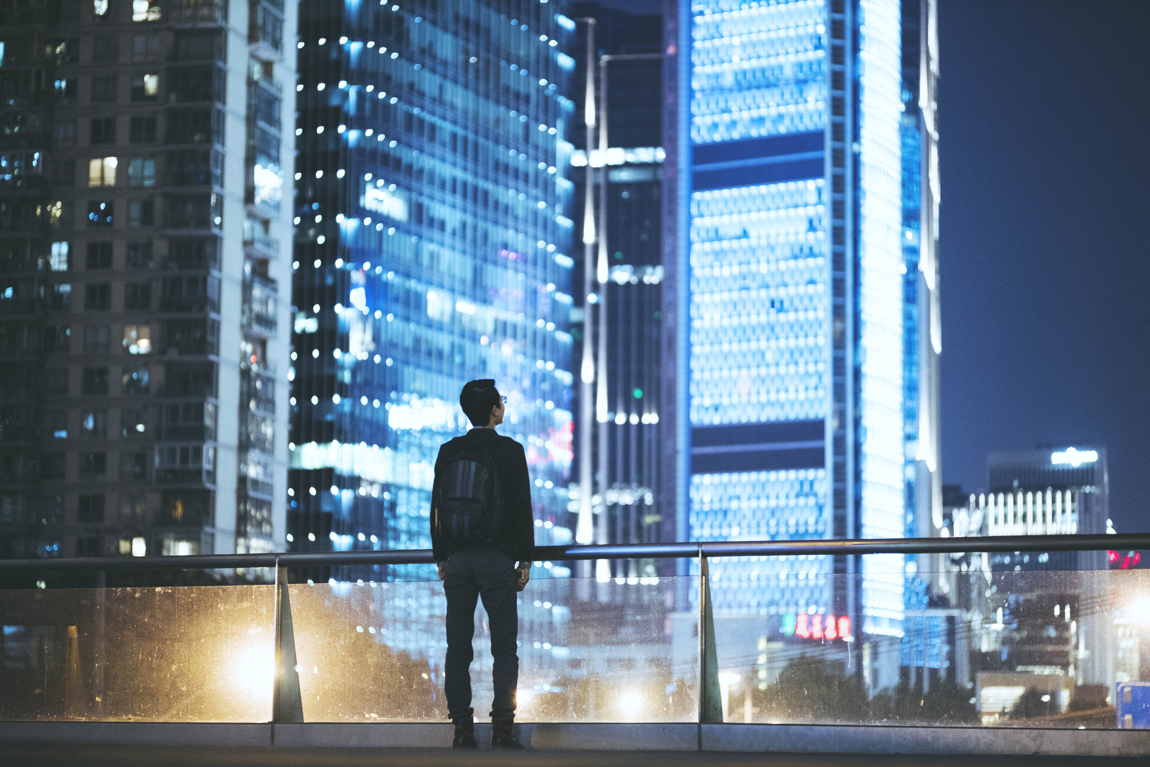 homem olhando para prédios de uma cidade a noite
