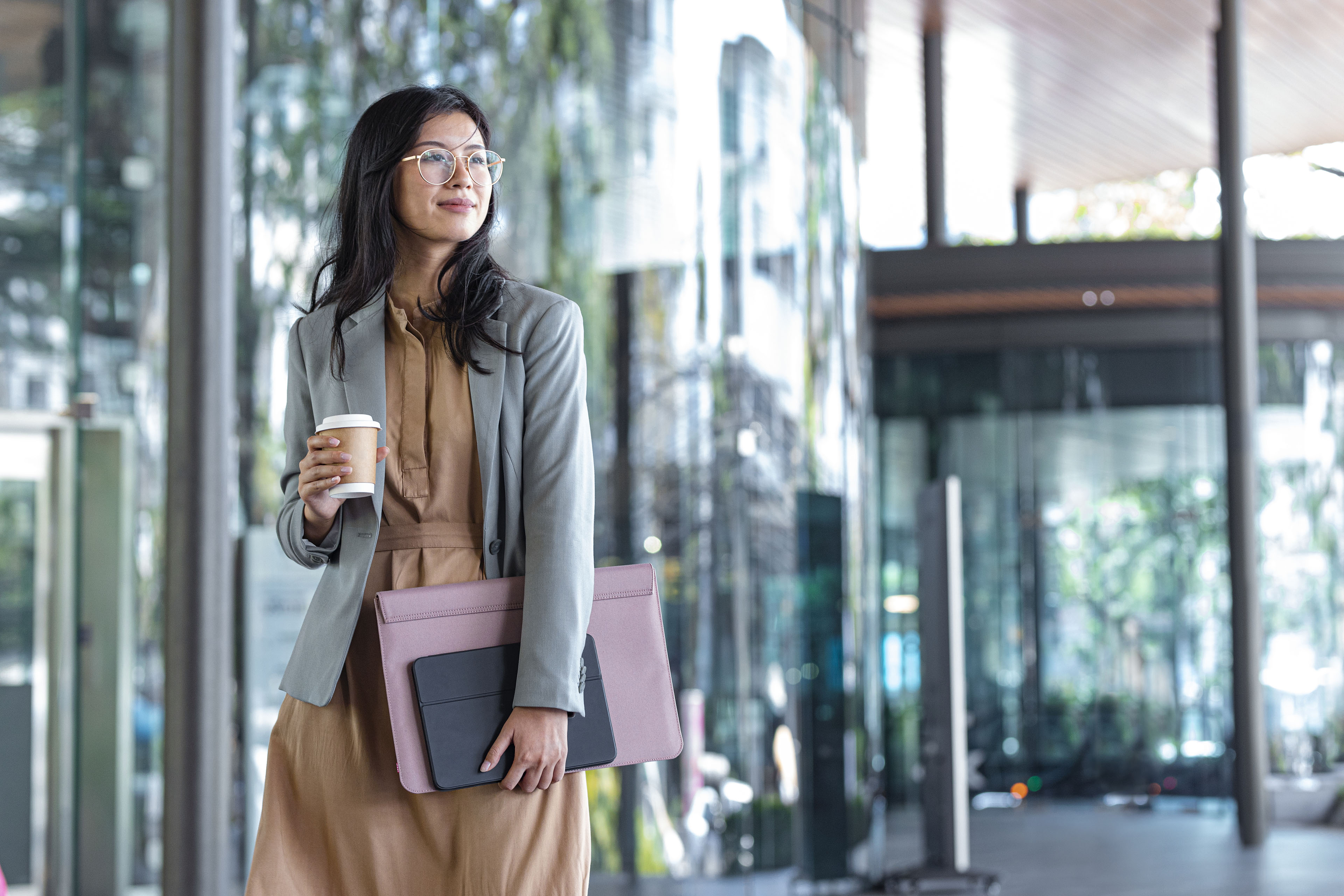 Mujer de negocios asiática con café junto al edificio de oficinas