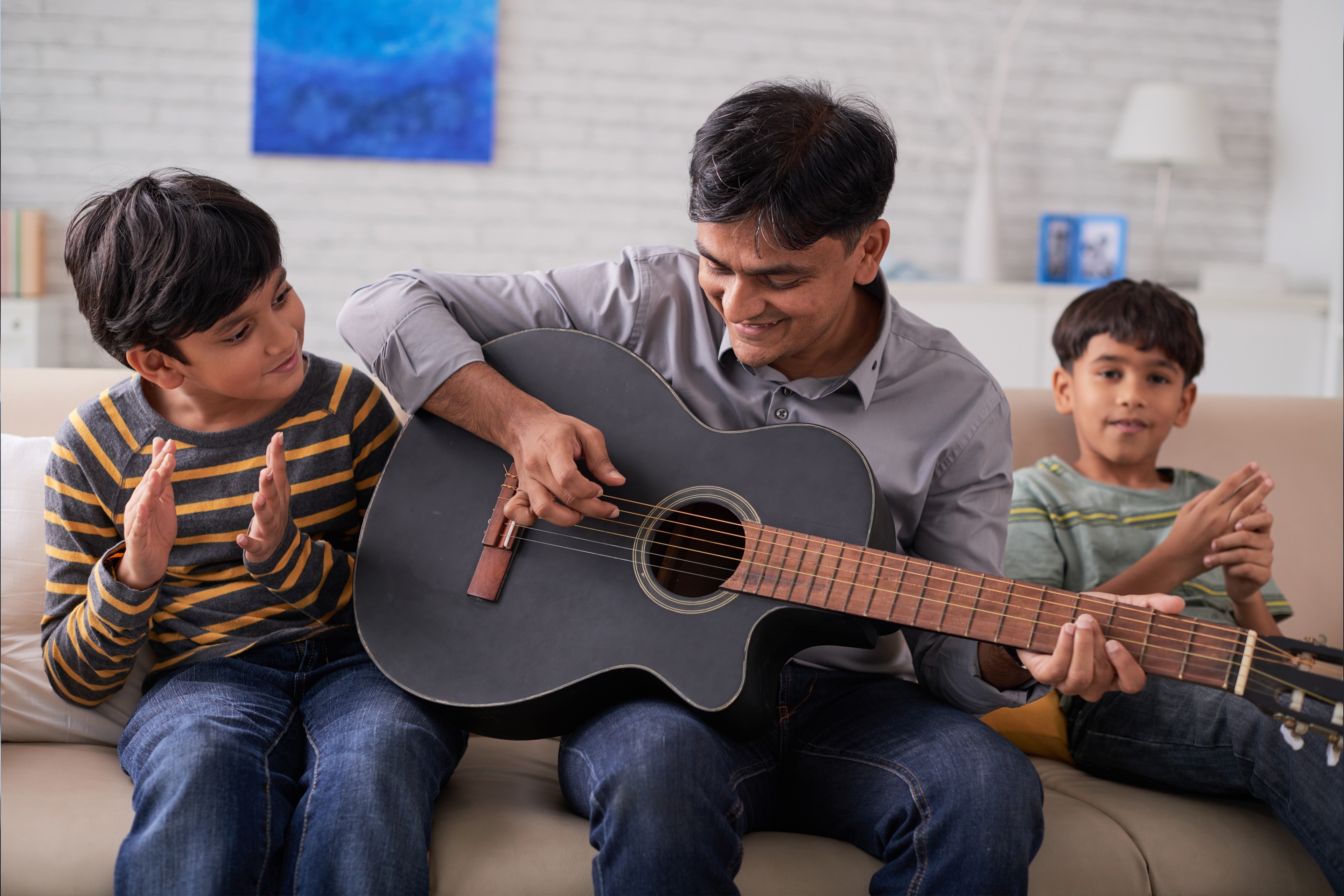 Padre tocando la guitarra mientras sus hijos cantan