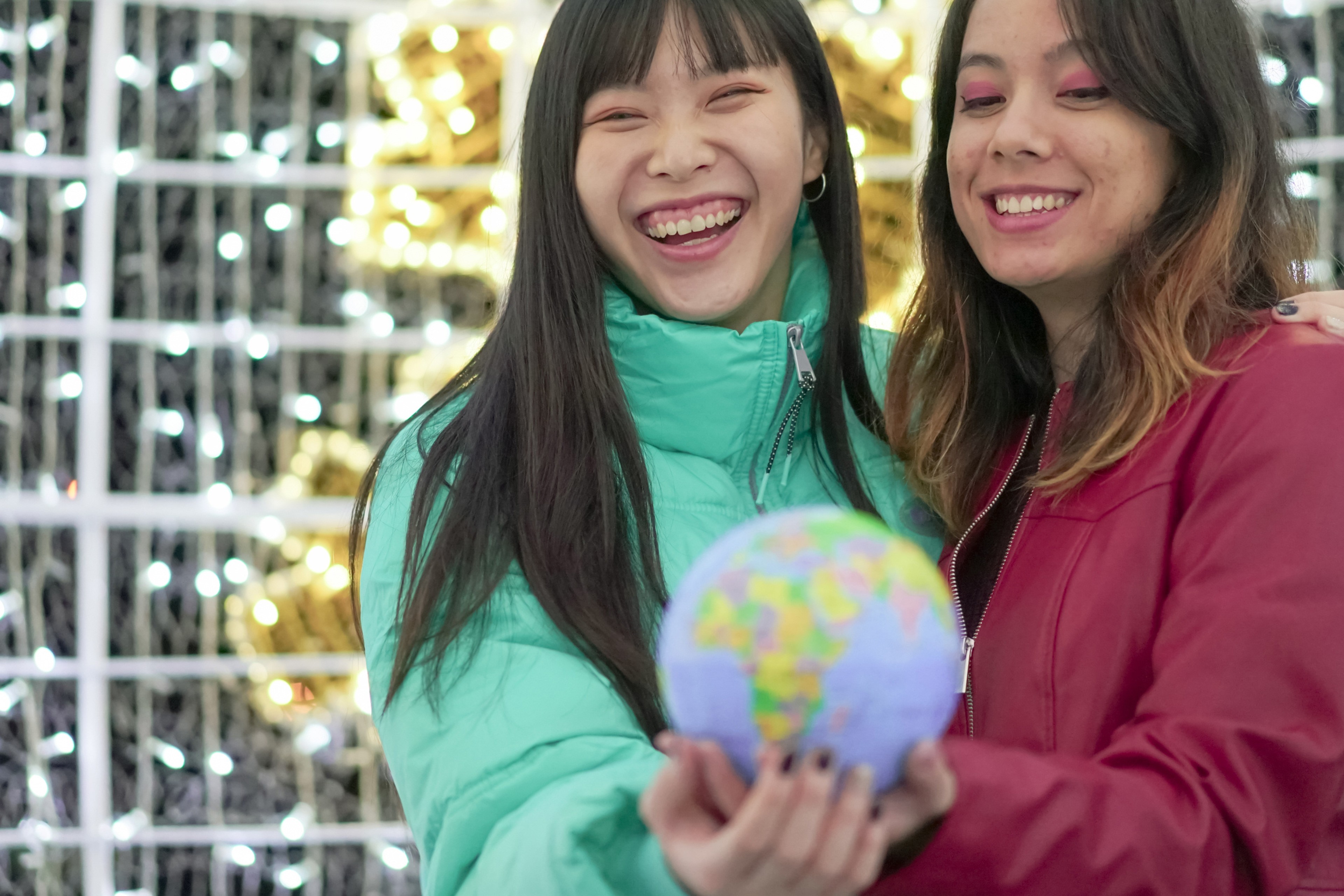 Two women holding model globe