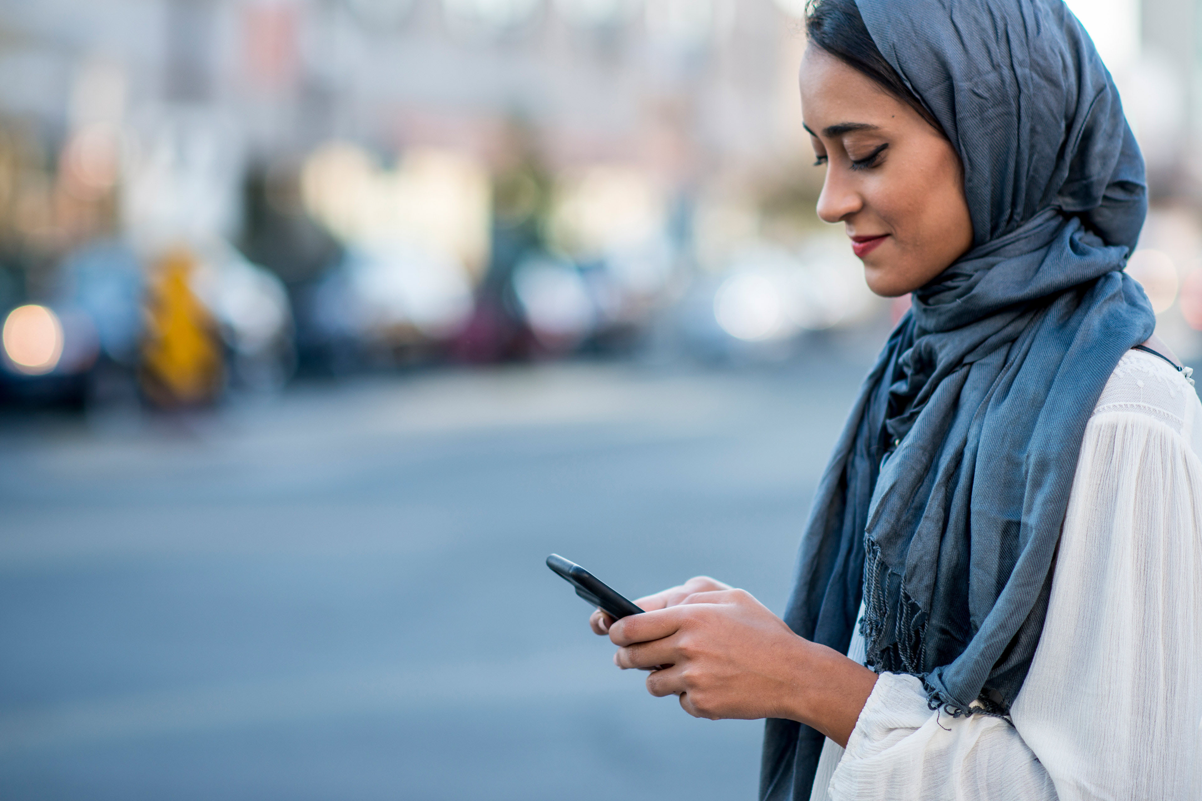 
            Mujer con pañuelo en la cabeza verifica su smartphone
        
