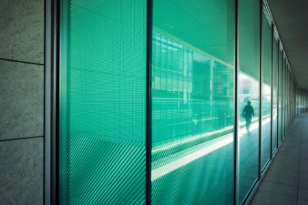 Colorful green glass facade of building reflecting city life
