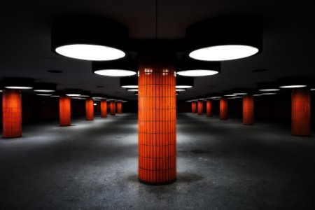 Columnas de azulejos naranjas y grandes luces redondas en estación de metro