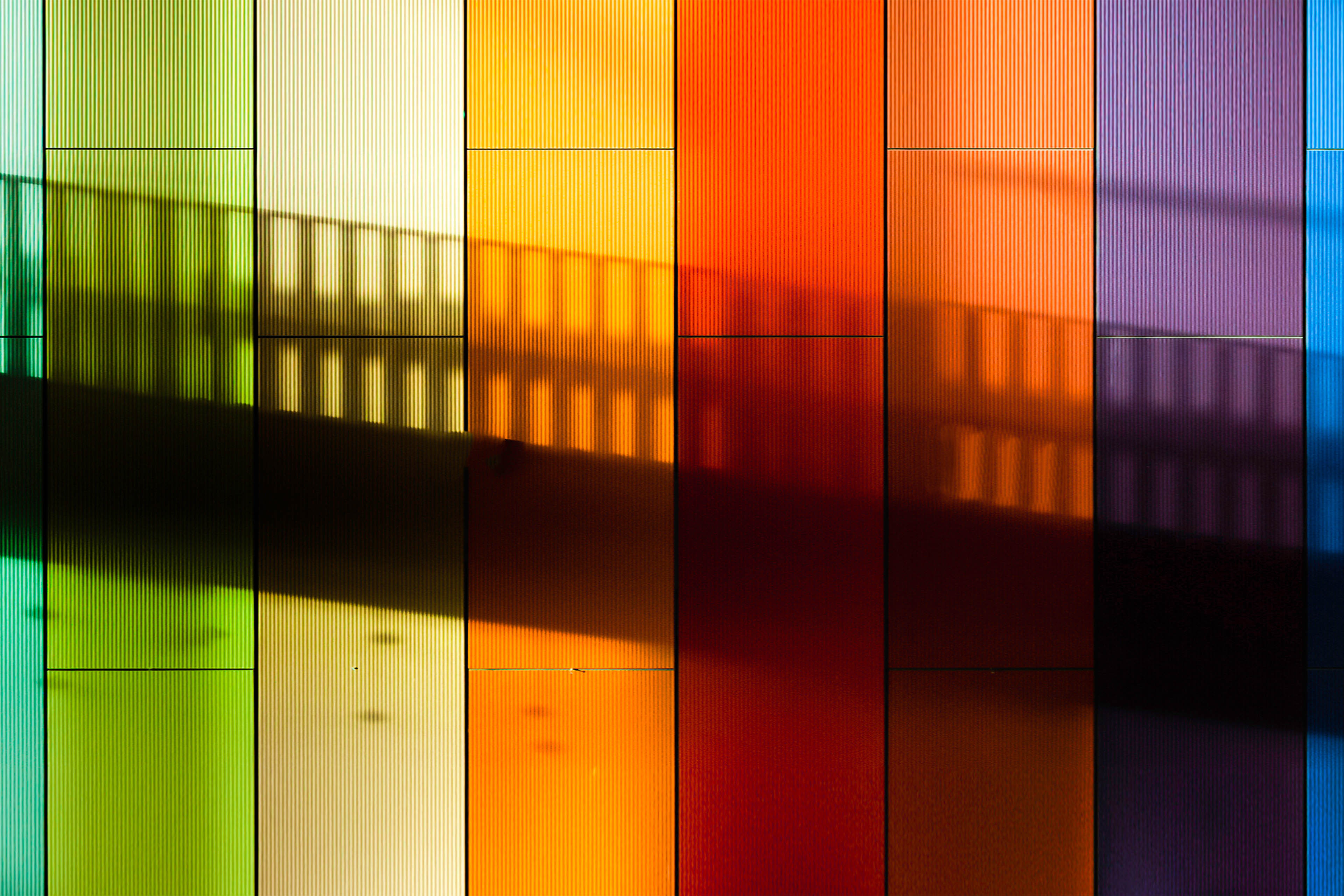 Shadow of a straircase on a rainbow striped wall