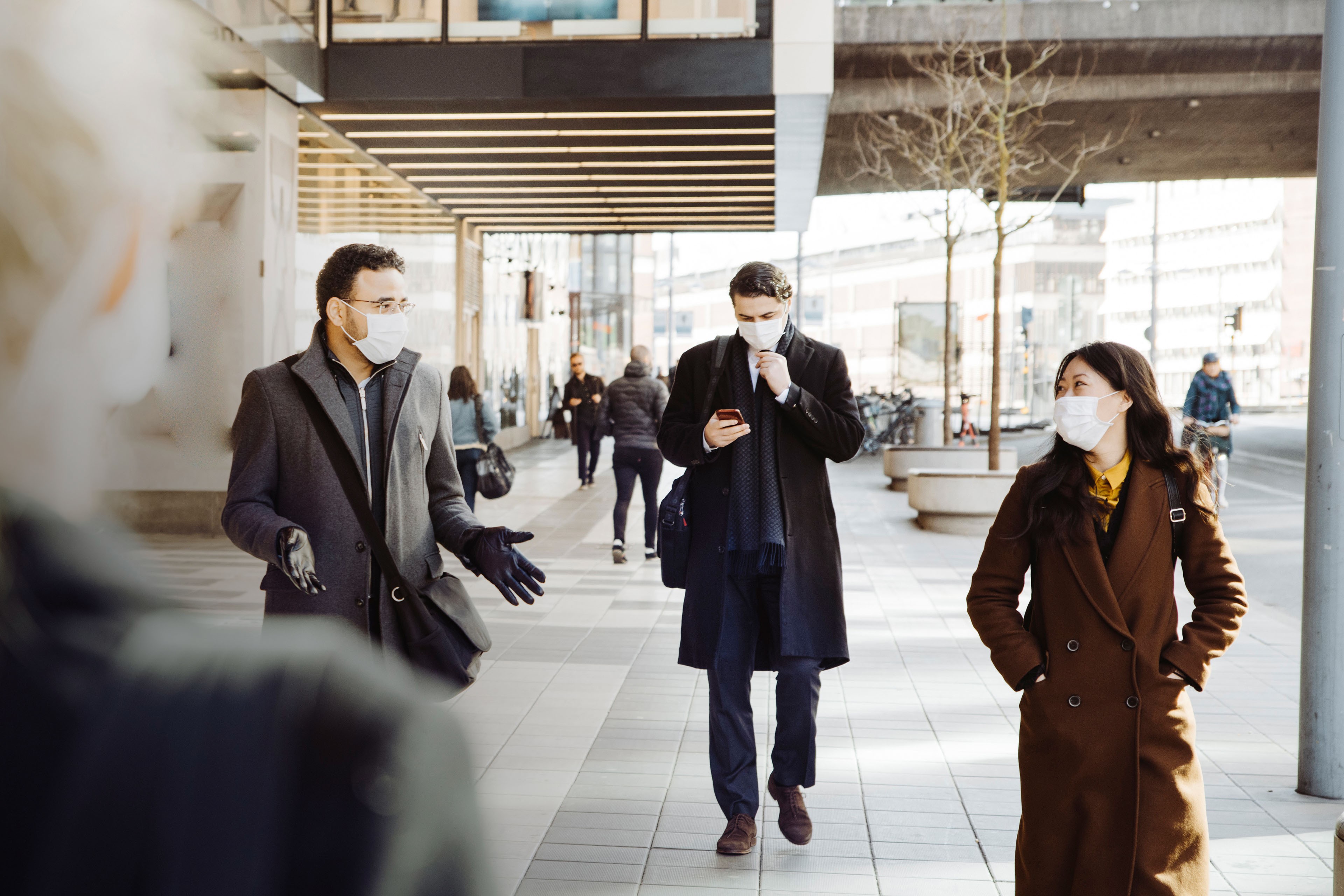 Business colleagues wearing masks talking on street