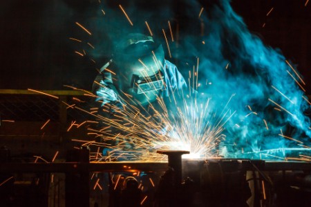 Worker welding in a car factory with sparks