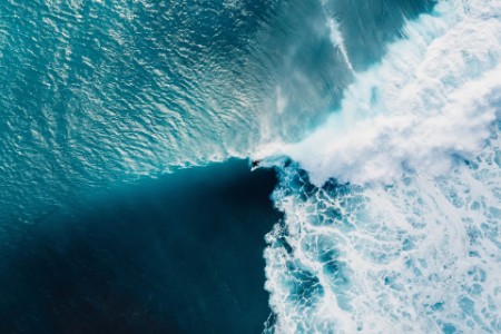 Aerial view with surfers and wave in crystal blue ocean