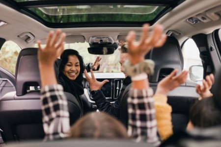 Cheerful family enjoying road trip in electric car