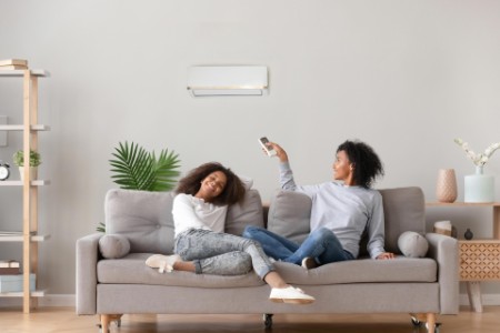 Family relaxing on sofa under air conditioner