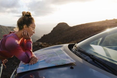 Side view of woman looking at the map on her car