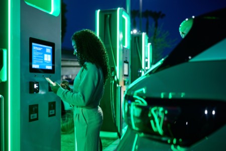 Woman standing at charging station during night