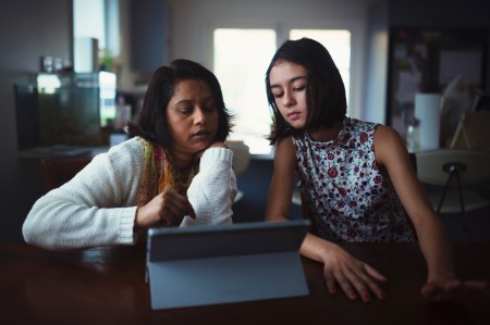A mother and daughter shop online with a tablet.