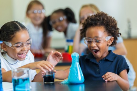 Las niñas de la escuela emocionadas durante el experimento de química