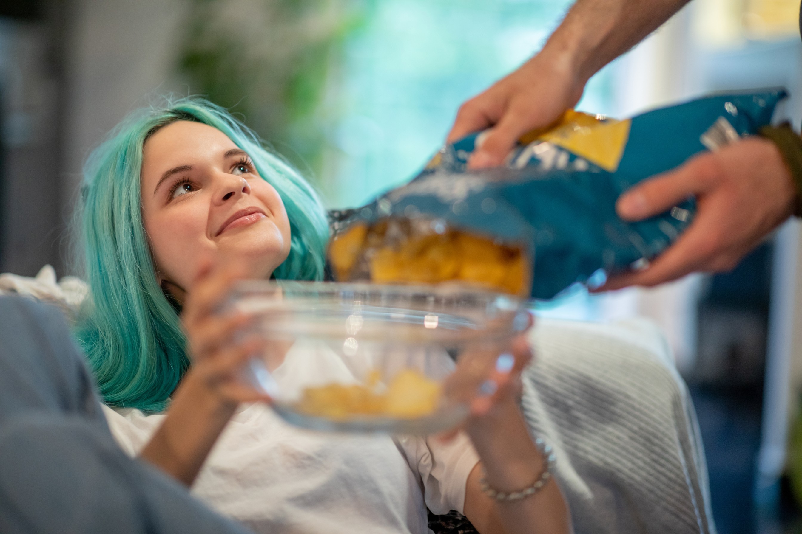 Rapariga com cabelo azul a pegar numa taça com batatas fritas