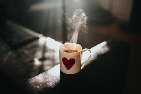 A hot mug of tea with a heart symbol on it.