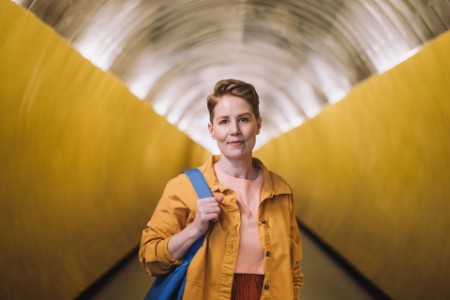 Retrato de una mujer con una bolso de color azul de pie en el túnel del metro