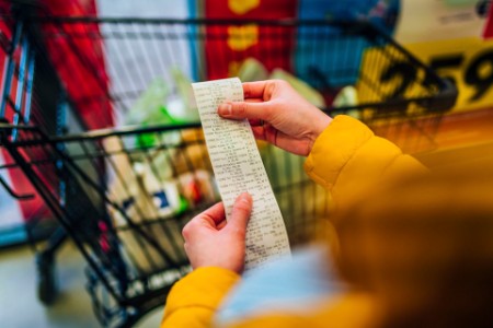 A photograph of a woman checking a shopping bill at a supermarket