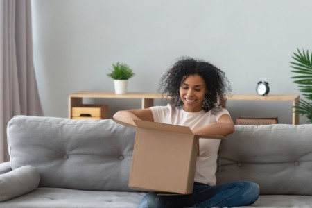 Woman sitting on a couch unboxing a parcel
