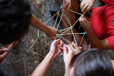 A high angle view photograph of friends making a model with rubber band and sticks