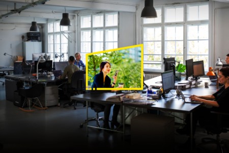 Imagen de la campaña Reframe your future que muestra un equipo de trabajo, con una mujer en un espacio verde en el centro.